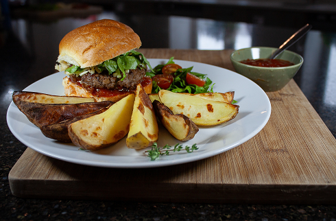 A homemade burger and chunky wedges served on a plate