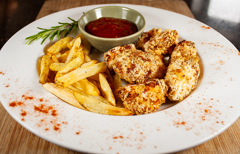 Homemade nuggets and chips served on a plate with ketchup