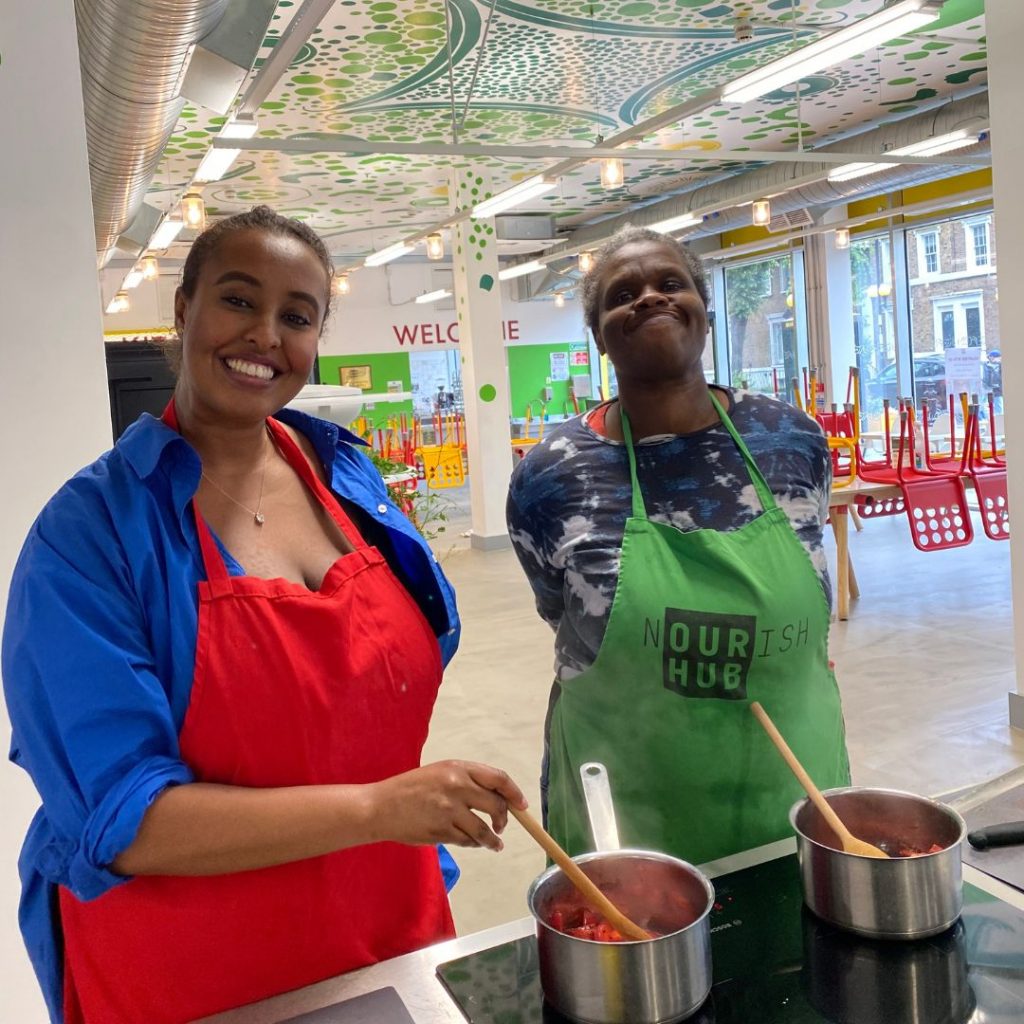 Two people cooking with saucepans at Nourish Hub