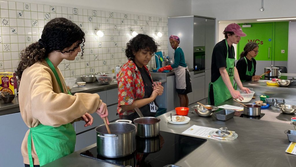 Group of adults cooking in the Nourish Hub training kitchen