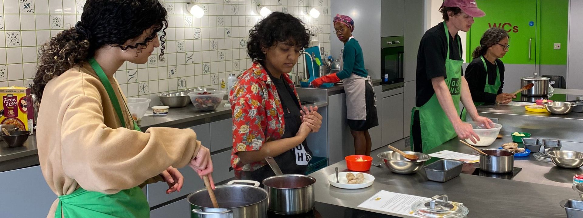 Group of adults cooking in the Nourish Hub training kitchen